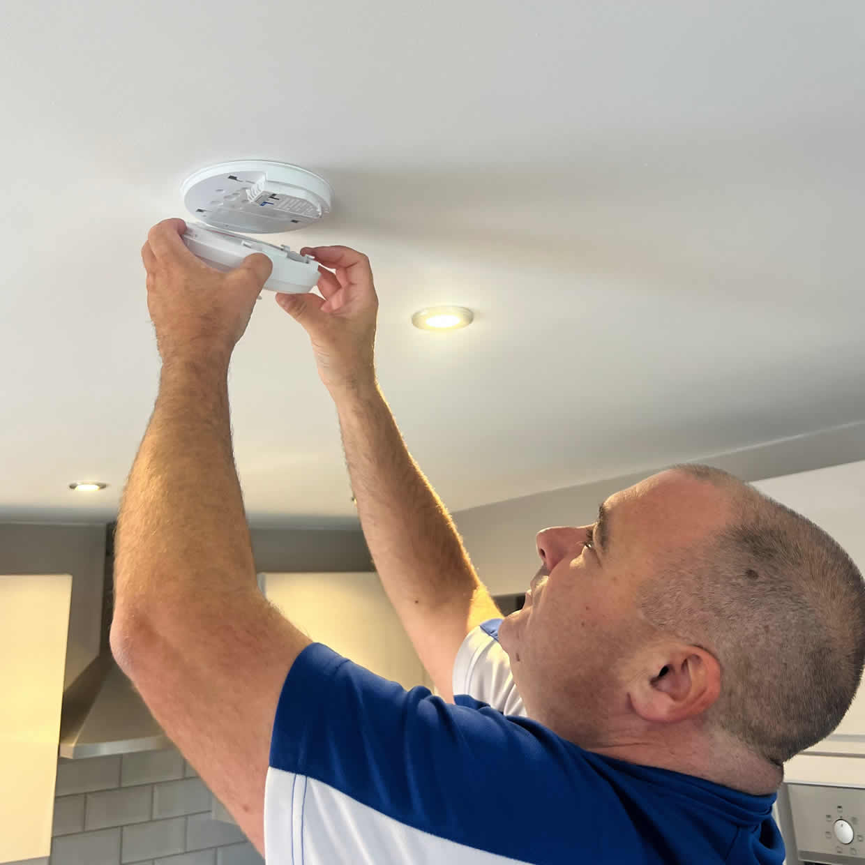 Smoke alarm being installed on a ceiling in Rugby